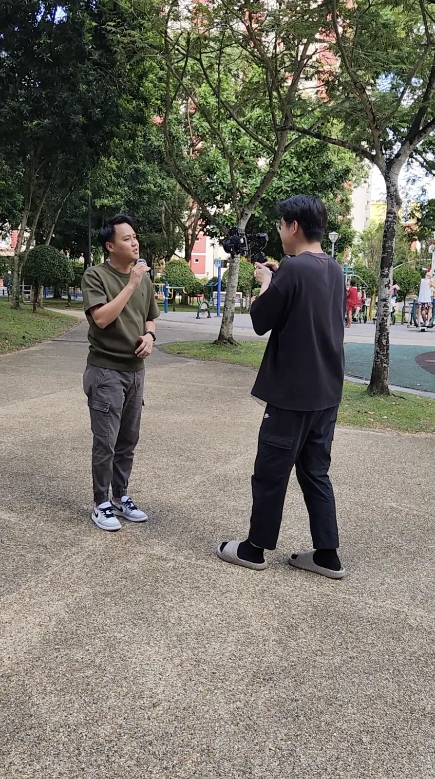 A Drealm production shoot on location in Singapore: a presenter on camera while a videographer films on a gimbal