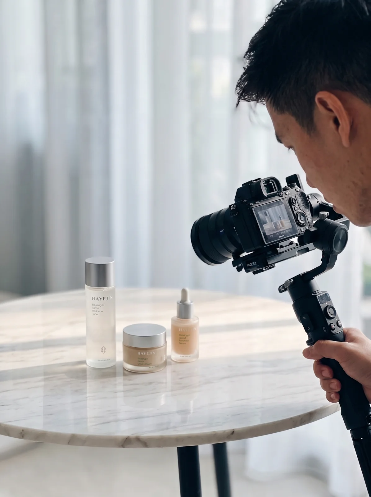 A Drealm videographer filming a skincare product set with a gimbal-mounted mirrorless